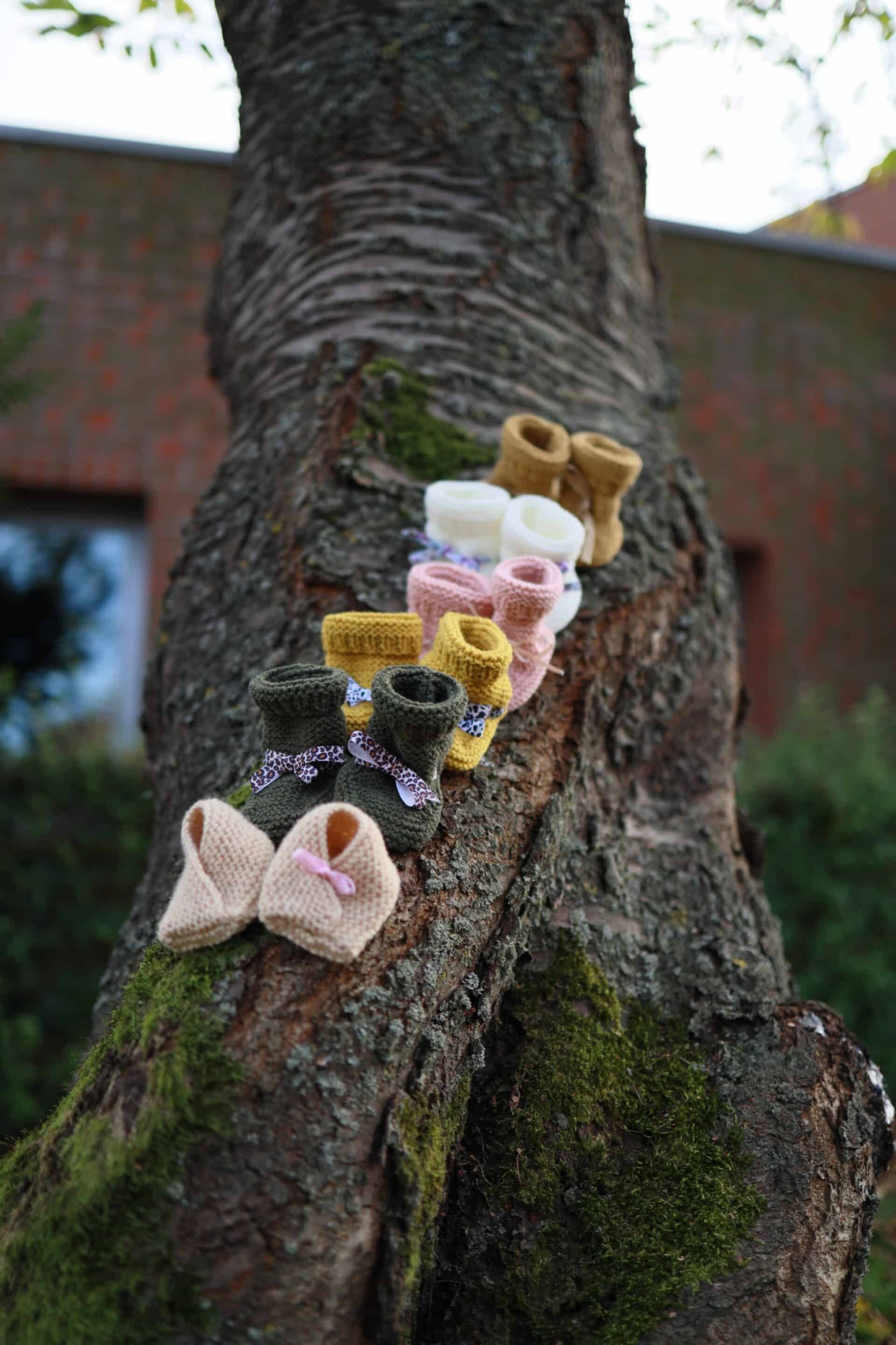 Chaussons pour bébé colorés suspendus à un arbre, décorations mignonnes et douces.