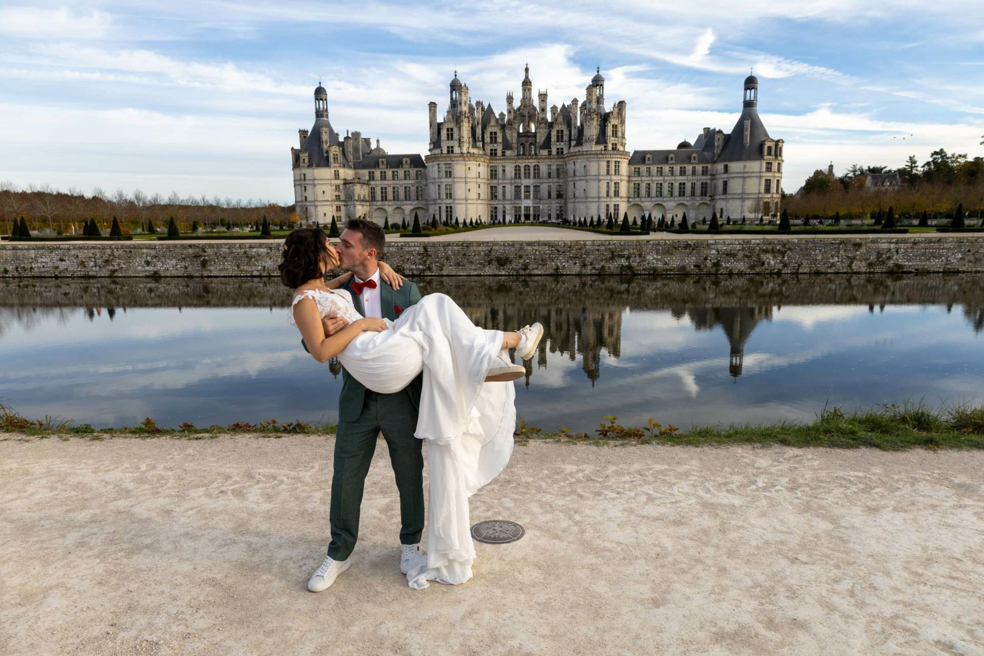 Photo de mariage avec un couple devant un château historique.
