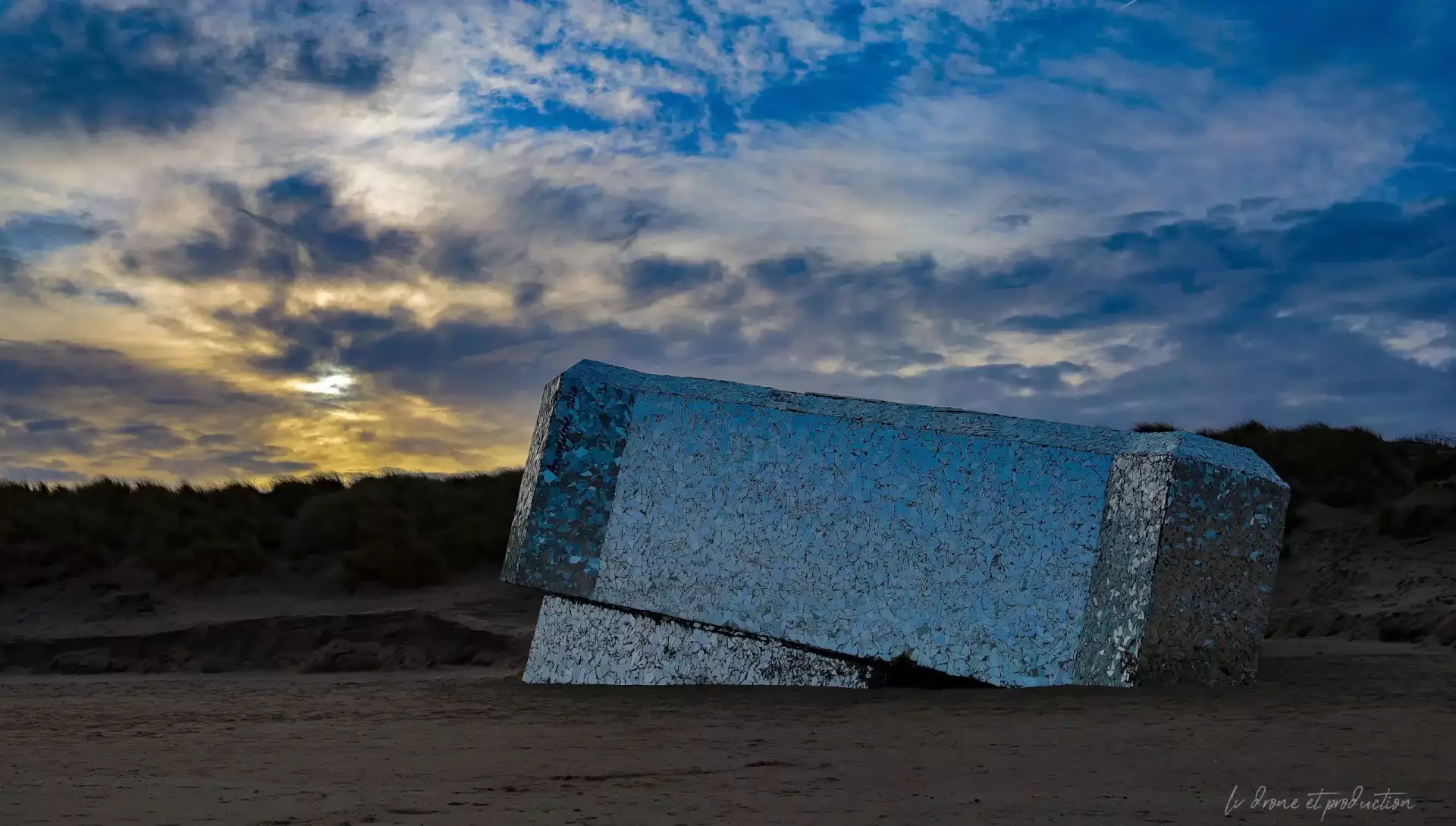 Brique géante en pierre sur la plage au coucher du soleil, photographie aérienne.